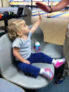 Charlie high fived her dad after he bowled a strike. 